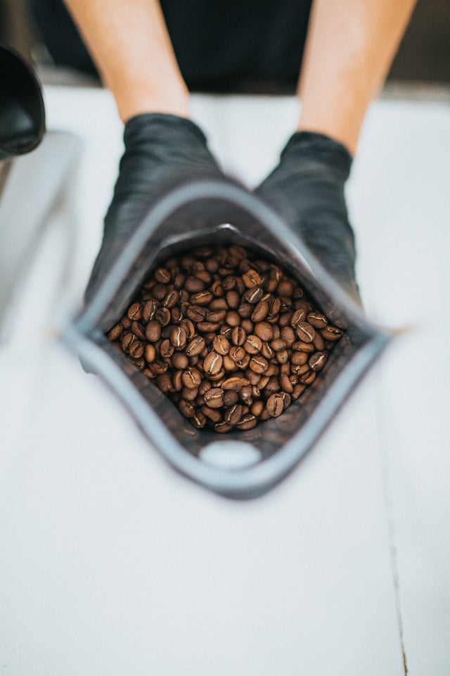 Roasted coffee in a bag being shown off by an employee.